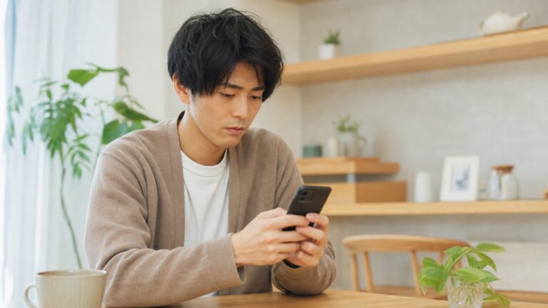 スマートフォンで「今何してる?」というLINEメッセージを受け取り、嬉しそうに画面を見つめる女性の写真