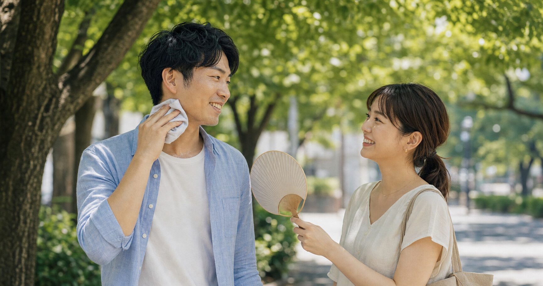 夏の屋外で汗を拭きながら笑い合う社会人カップルの後ろ姿の写真