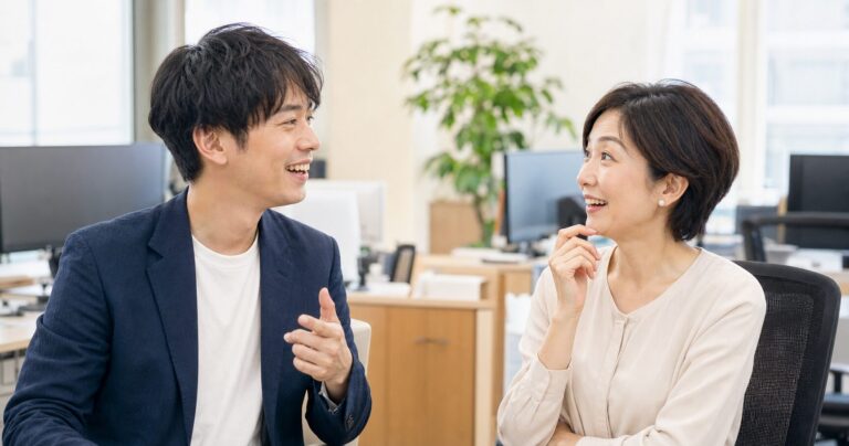 職場でからかうように話しかける年下男性と、困りながらも笑顔を見せる年上女性の写真