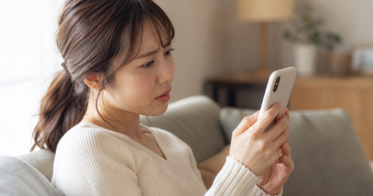 デートの日程は決まったのに相手から連絡が来ず、スマホを見つめて考え込む女性の写真