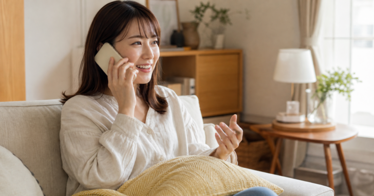スマートフォンで通話しながら笑顔で話す女性の写真