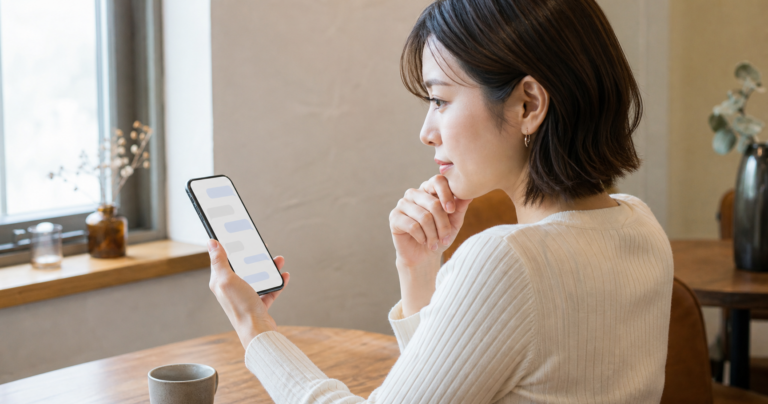 スマートフォンでマッチングアプリのメッセージ画面を見ながら、2回目のデートの誘いへの返信を考えている女性のイラスト