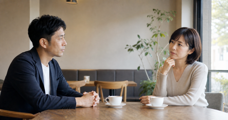 既婚者の男性とカフェで向かい合って座る女性、不安げな表情のイメージ