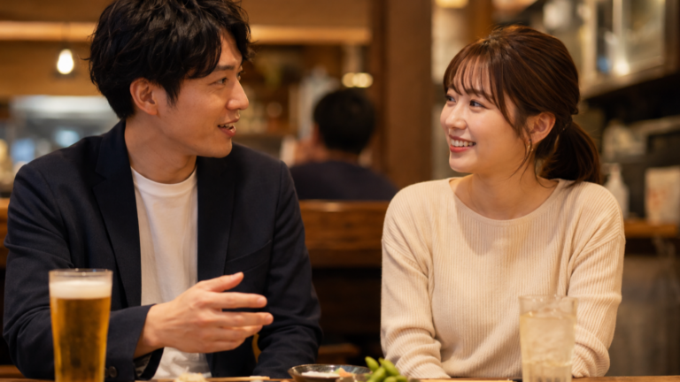 居酒屋のテーブルで隣どうしに座り、笑いながら軽く肩に触れている男女のイラスト