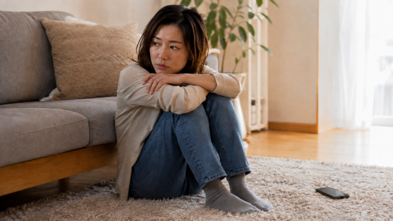 喧嘩をした後、スマートフォンを手に複雑な表情で考え込む女性の写真