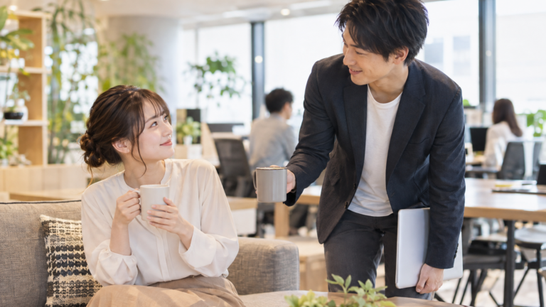 職場でさりげなく相手を気遣いながら会話する二人の写真