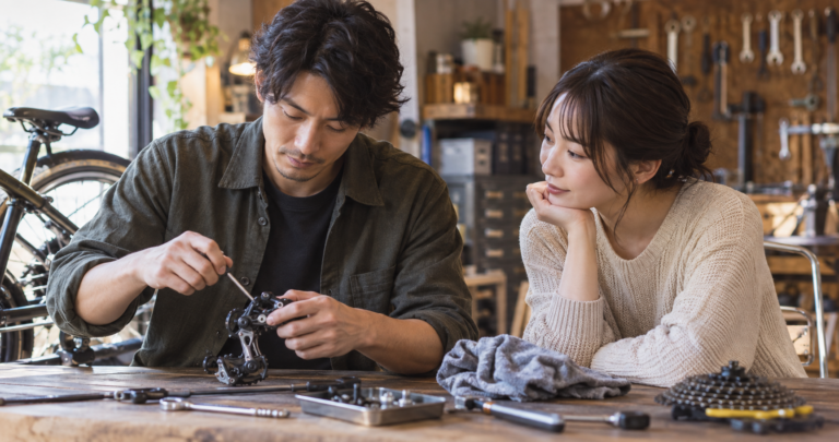 作業中の手元を見せながらそっと隣に座る男性と、気になる表情で見つめる女性の写真
