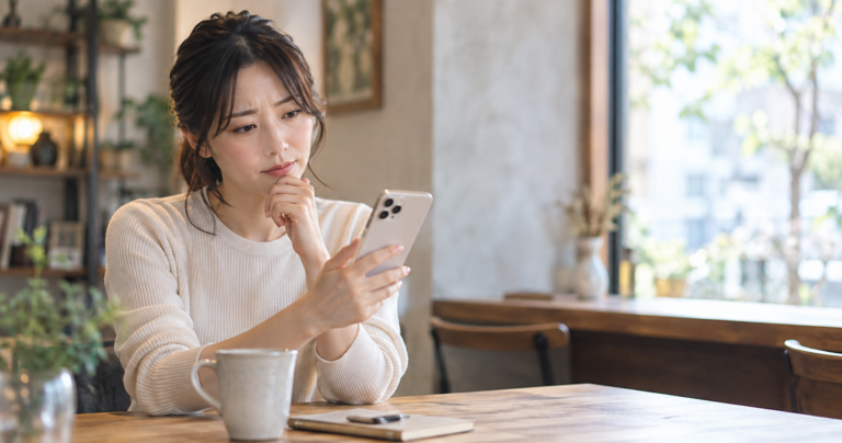 マッチングアプリで顔写真のやり取りについて考えながらスマートフォンを操作する人物のイメージ