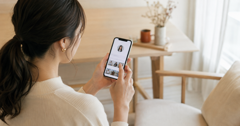 スマートフォンでマッチングアプリのプロフィールを見直す20代後半の女性の写真