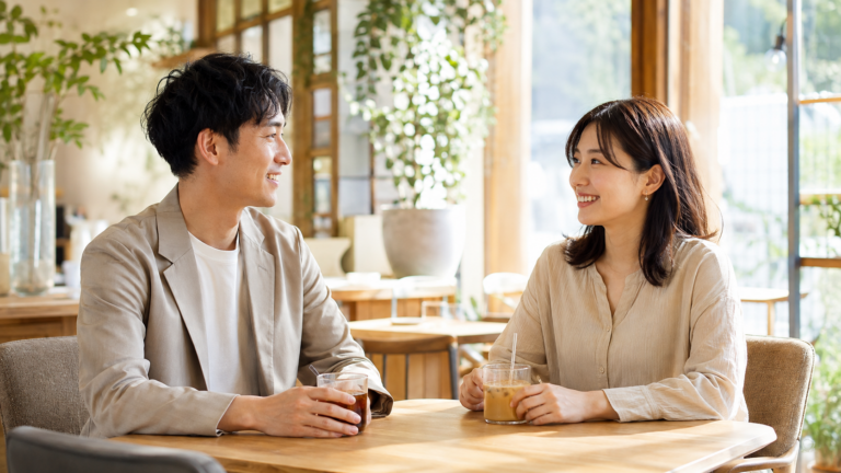 マッチングアプリで知り合った男女が、2回目デートの待ち合わせ場所となるカフェの前で笑顔で話している様子のイラスト