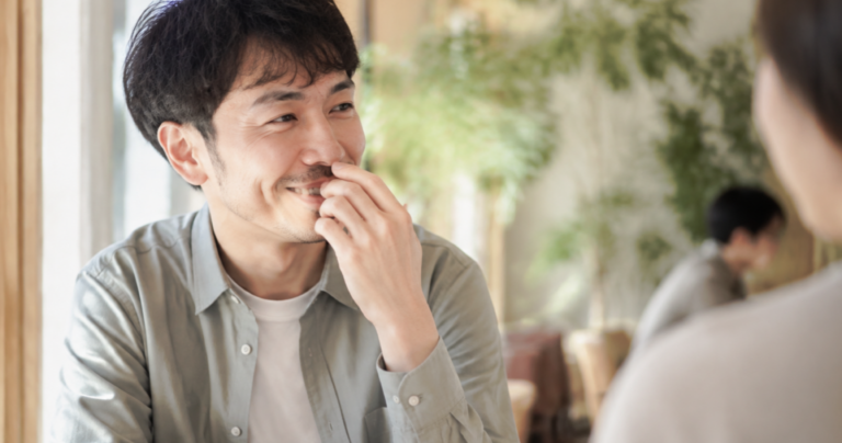 会話の途中で口元を気にして自然に手を添える男性の横顔