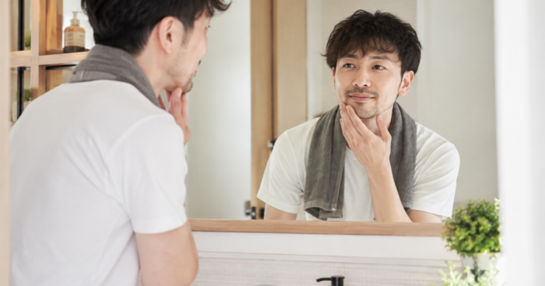 鏡の前で肌や表情を気にしながら身だしなみを整える男性の様子