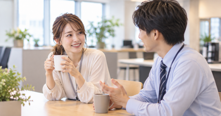 オフィスで会話をしながら親しくなっていく男女社員の写真