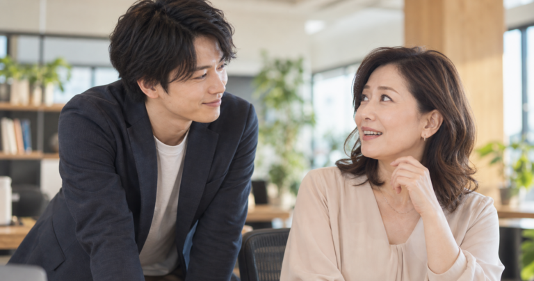 年下の男性と自然に会話しながら微笑む年上女性の写真
