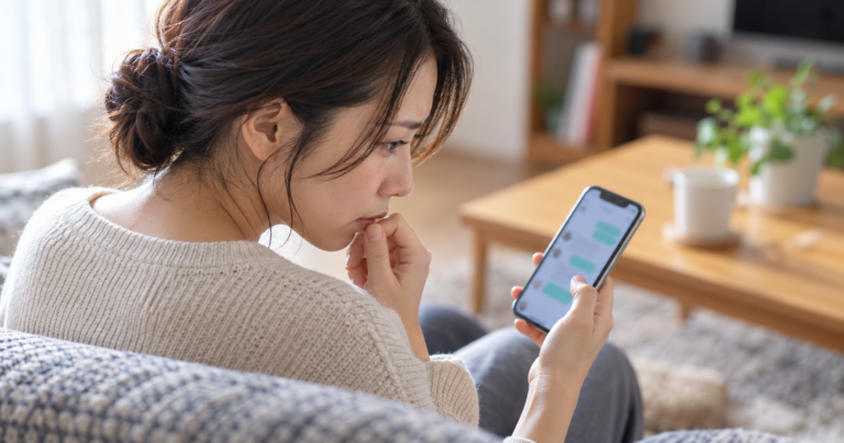 スマートフォンの画面を気にしながら思い悩む様子の男女のイメージ写真